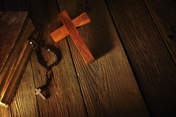 Christian cross on wood bible and rosary beads over wooden vintage background