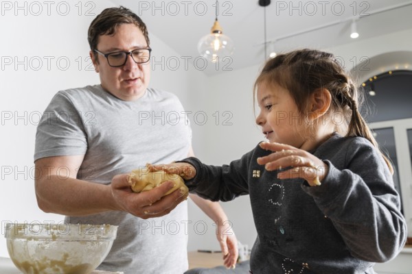 Father feeling playful with his caucasian little daughter, while preparing homemade dough for tasty cookies. Father and his child spending time at home .