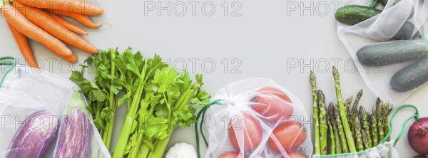 Fresh organic vegetables in eco reusable produce shopping bags flat lay, top view with copy space on gray background. Sustainable lifestyle. Zero waste, plastic free concept