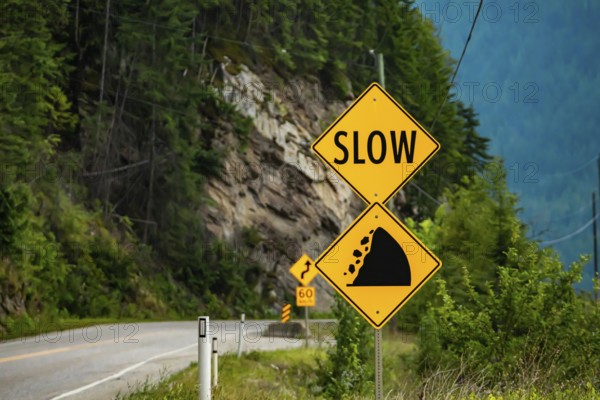 Slow, Watch for fallen rock and be prepared to avoid a collision, Warning yellow roads signs in selective focus view with rocky slope background