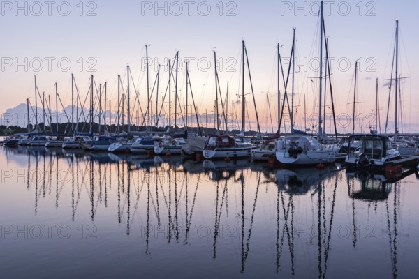 Sailing boats in the harbour reflecting in the water during beautiful sunset