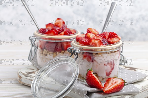 Parfait with Fresh Strawberries, Yoghurt and Crunchy Granola in Transparent Glass Mason Jars on White Rustic Wooden Background from Angle View, Healthy Breakfast or Light Summer Fruit Dessert, food photography, food photography