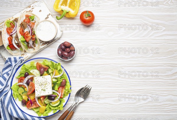 Traditional Greek Food: Greek Salad, Gyros with meat and vegetables, Tzatziki sauce, Olives on White rustic wooden table background from above. Cuisine of Greece. Copy space, food photography, food photography