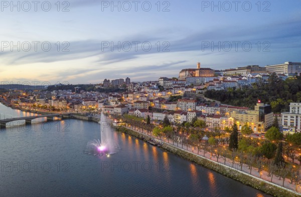 Coimbra drone aerial city view at sunset with colorful fountain in Mondego river and beautiful historic buildings, in Portugal