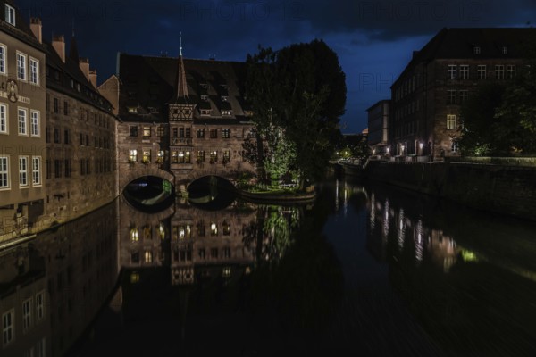 Neurenberg, Bavaria, Germany, 07 26 2018: Tourists viewing old town, reflected in the water at night, Europe
