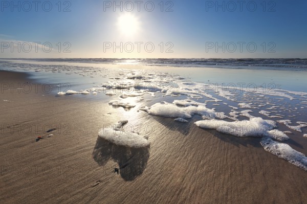 Sunshine over North sea waves on beach, Netherlands