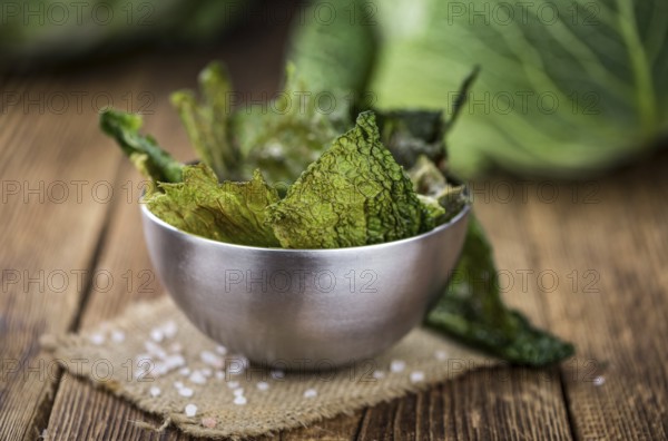 Healthy Savoy Chips on a wooden table as detailed close-up shot (selective focus)