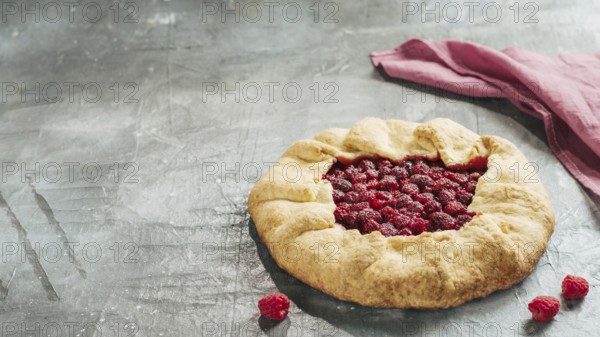 Perfect raspberry galette. Delicious rustic homemade tart with frozen or fresh raspberries on gray background. Beautiful round shape galette with raspberries, copy space