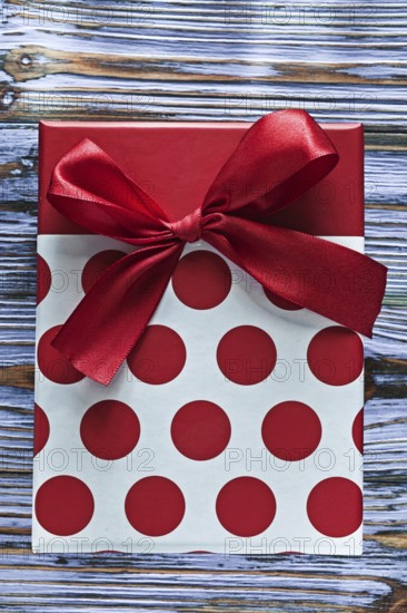 Red present box with ribbon on vintage wooden board