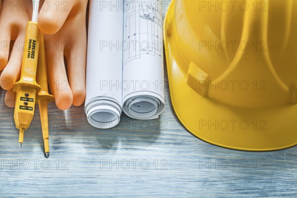 Electric tester building helmet dielectric gloves engineering drawings on wood board electricity concept
