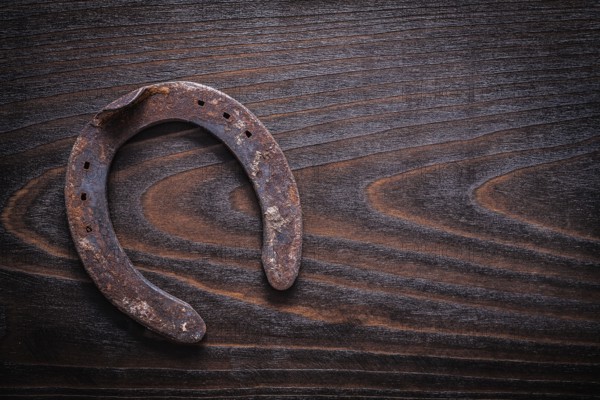 Rusted obsolete horsehoe on vintage dark wood board copy space image construction concept