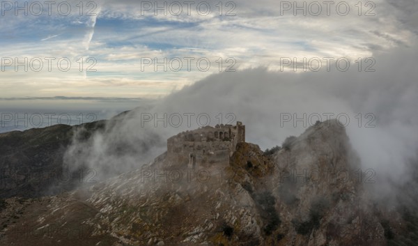Magazzini, Italy, 14 November, 2023: drone view of the Castello del Volterraio shrouded in morning fog and cloud, Europe