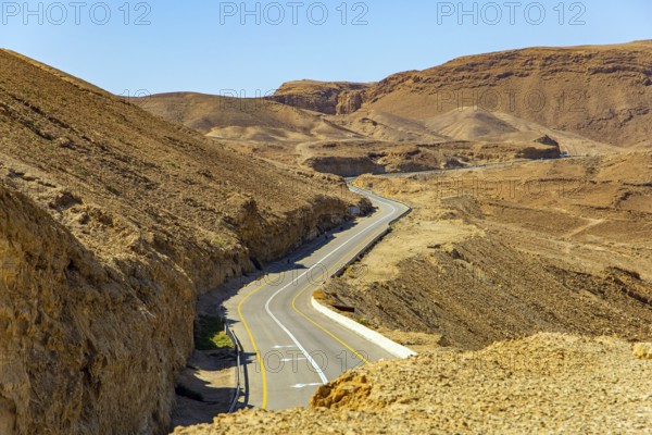 Israeli coast, warm winter February day. Asphalt highway in the ancient mountains on the shores of the Dead Sea. Israel. The saltiest lake in the world