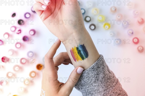 Rainbow LGBTQ flag painted on hand. Support for lgbt community. Honour of pride month. Connecting people, touching hands. Multi colored hands art creativity, discrimination