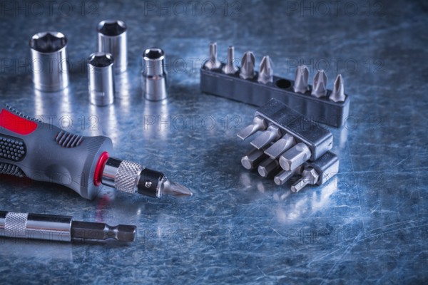 Toolset of screwdriver with stainless replaceable bits and torx on scratched metallic background construction concept