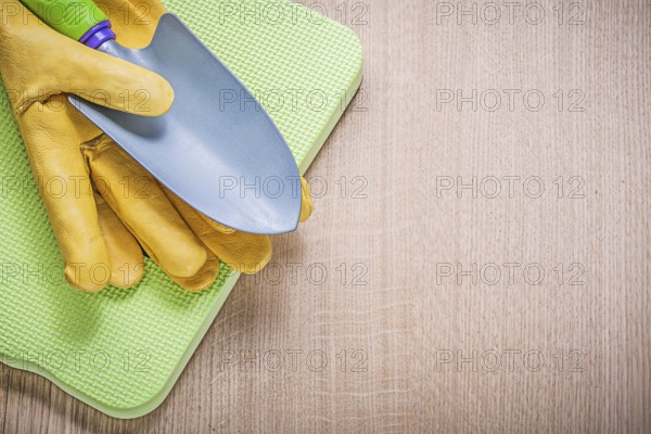 Protective gloves metal hand spade foam gardening kneeling pad on wooden board agriculture concept