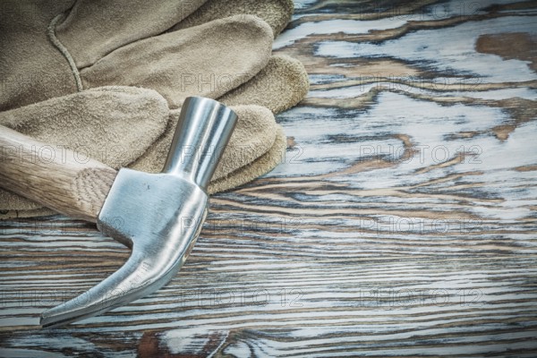 Pair of protective gloves claw hammer on wooden board