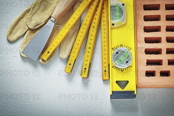 Red brick protective gloves putty knife construction level wooden meter on concrete background bricklaying concept