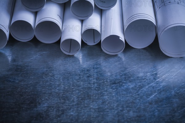 Rolls of white blueprints on scratched metallic background building and architecture concept