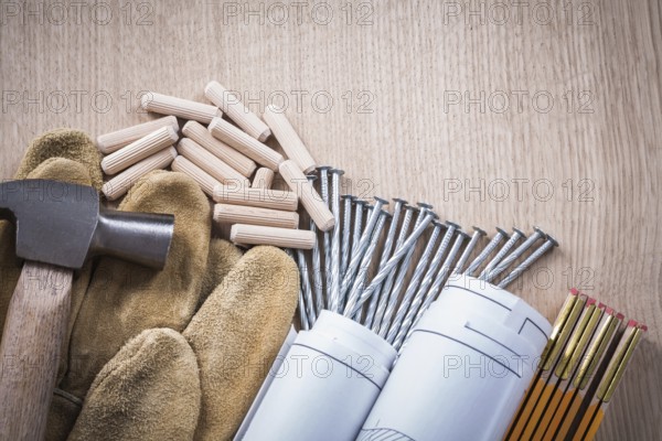 Collection of wooden meter dowels construction drawings claw hammer leather safety gloves and steel nails on wood board maintenance concept