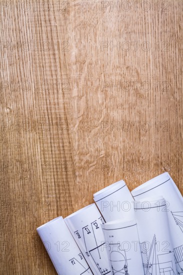 Stack of white construction rolled up blueprints on wooden boards with copyspace