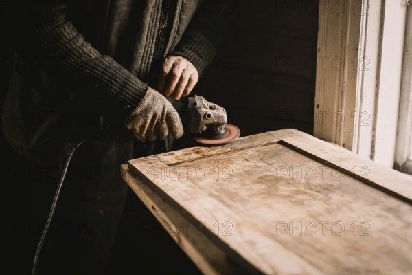 A person using a power tool to sand wood at a workbench