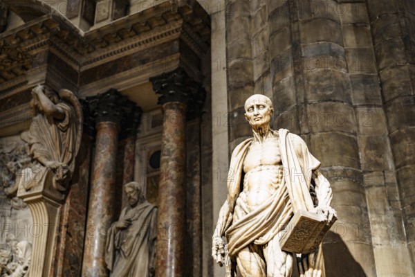 Statue of Saint Bartholomew with a book in his hands in the Duomo. Italy, Milan.