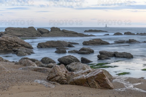 Rocks on the beach in the evening with moving water which brings an effect to the surface of the sea in France