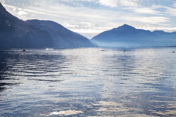 Amazing view of Lake Lugano with mountains on the other side of Lake Lugano and kayaks with athletes (competetions) in them. Photo from the Olive Trail on the coast