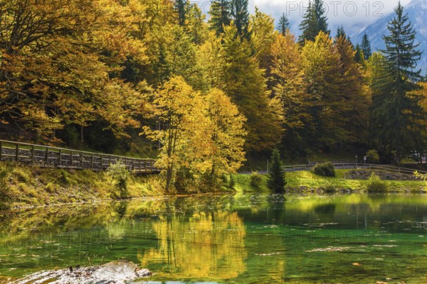 Fantastically beautiful autumn forests are reflected in the water. The quiet lake in Northern Italy, Lago de Fusine. Concept of cultural and ecological tourism. High water of the lake after a rain