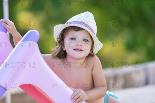 Baby kid girl with hat in summer on green field background