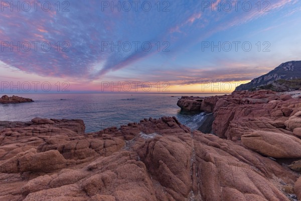 Large red rocks at the edge of the sea under a cloudy evening sky, Spiaggia di Cala E'Luas, Ogliastra, Sardinia, Italy, Europe