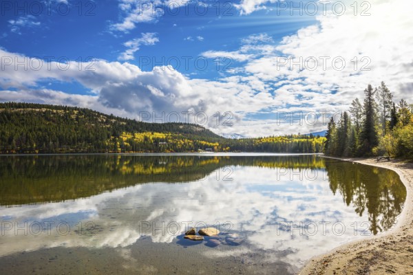 Pyramid Mountain and cumulus clouds is reflected in Pyramid Lake. Cold autumn morning in the Rocky Mountains, Canada, North America
