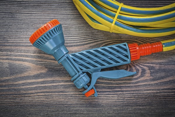 Garden hose coil water hand spray gun on wooden board agriculture concept