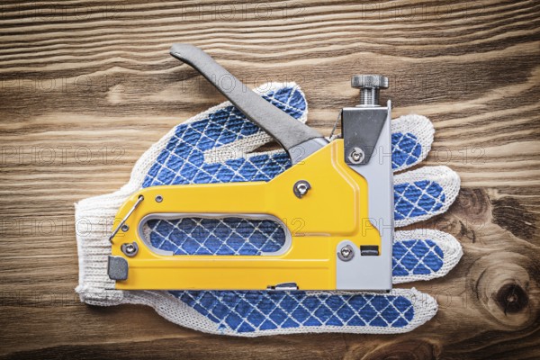 Stapler gun pair of working gloves on wooden board construction concept