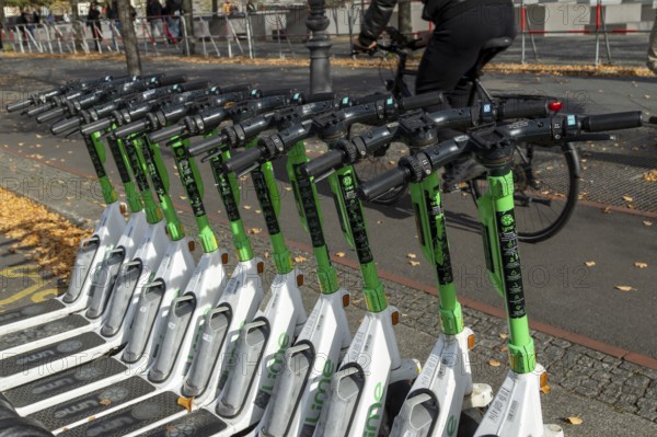 Traffic, mobility, cyclists and lined-up e-scooters from Lime in autumn on a street in Berlin, Germany, Europe