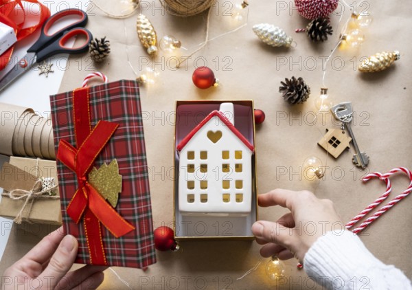 Key to house with keychain on cozy home in gift box with Christmas decor packaging. Pack present for New Year, Christmas. Building, project, moving to new house, mortgage, rent, purchase real estate