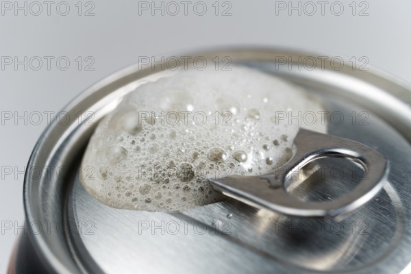 Close-up detail of a beer can with foam on a white background with space for text