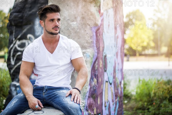 Handsome fit man in white t-shirt outdoor in city setting, looking away