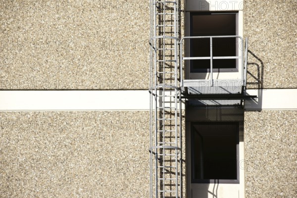 A fire escape on the side of a residential building casts a shadow