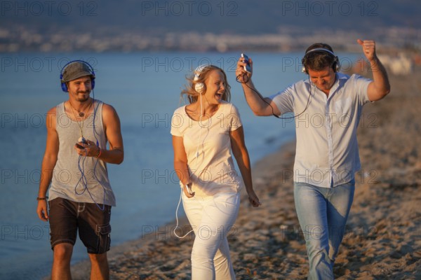 Excited friends outdoor. Young people relaxing and having fun listening to music in headphones