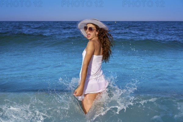 Girl in beach sea shore with waves splash and summer white dress