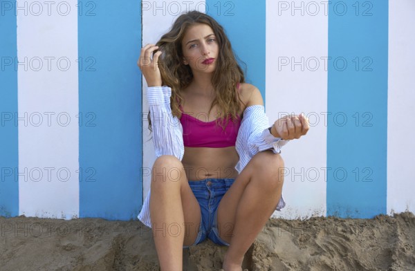 Brunette teen summer girl in a blue stripes wall background