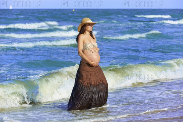 Pregnant woman on the beach playing with waves