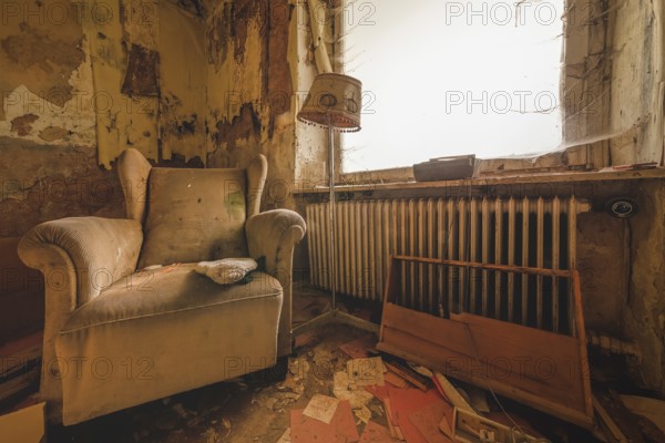 An outdated room with armchair and lamp next to a neglected heating system, Lost Place, Urologist's Villa Dr Anna L., Bad Wildungen, Hesse, Germany, Europe