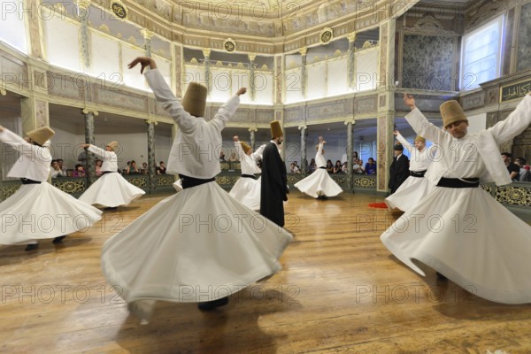 Dancing dervishes, dervish dance Sema, Mevlevihanesi Müzesi at Istiklal Caddesi, Istanbul, European part, Turkey, Asia, A group of dervishes dances synchronously in white robes on a wooden floor surrounded by spectators, Istanbul province, Dancers perform traditional spinning movements in a magnificent historical room with audience, Istanbul Modern, Asia