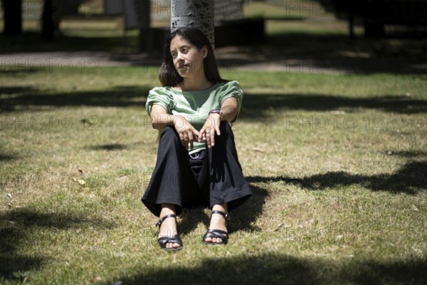 Latin woman sitting in a park with a thoughtful expression