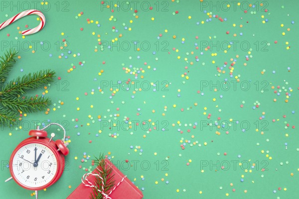 New Year or Christmas pattern flat lay top view with red alarm clock twelve midnight fir tree branch Xmas holiday celebration green paper bright colorful confetti background. Template text design 2019