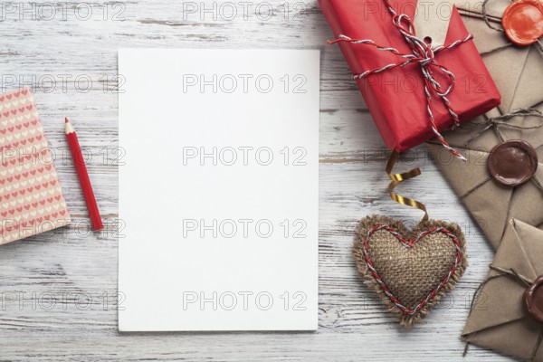 Flat lay composition with handmade fabric heart and gift box. Blank sheet of white paper on wooden surface. Romantic Saint Valentine's day congratulation. Baby born card. Wedding event invitation