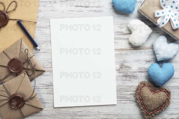 Flat lay cute composition with handmade fabric heart. White paper and retro mail envelopes on wooden table. Happy birthday or anniversary congratulation. Romantic message template with copy space
